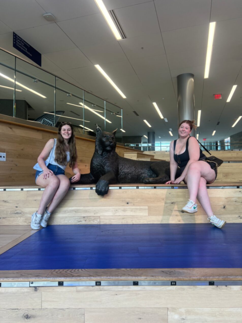 Bruna e amiga com a estátua do mascote na universidade